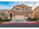 Two-story house with tan exterior, beige garage door, and landscaping at 221 Gemstone Hill Ave, North Las Vegas, NV 89031