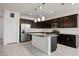 Modern kitchen featuring dark cabinetry, granite island, and white subway tile backsplash at 6411 Ranunculus St, North Las Vegas, NV 89084