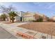 House exterior showcasing a tan facade, two-car garage, and a neatly landscaped yard at 9515 Parvin St, Las Vegas, NV 89123