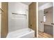 Clean bathroom with a white bathtub, wood-look accent wall, and marble-look tile at 5101 Village Dr, Las Vegas, NV 89142