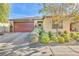 Single-story home with landscaped front yard, red door, and two-car garage at 5732 Swan Bridge St, North Las Vegas, NV 89081