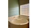 Relaxing bathtub in a bathroom with a block window and soft green walls at 10809 Sleepy River Ave, Las Vegas, NV 89144