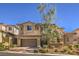 Two-story house with tan exterior, brown garage door, and landscaped yard at 12048 Portamento Ct, Las Vegas, NV 89138