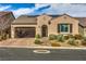 Tan stucco house with brown garage door and landscaped front yard at 3428 Isle Dr, Las Vegas, NV 89141