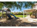 Backyard with covered patio, playground, and grassy area at 10301 Horseback Ridge Ave, Las Vegas, NV 89144