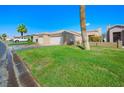 Single-story home with two-car garage and lush green lawn at 1199 Golf Club Dr, Laughlin, NV 89029