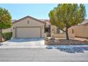 Single story home with tan exterior, two-car garage, and desert landscaping at 7824 Homing Pigeon St, North Las Vegas, NV 89084