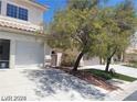 Two-story house with a two-car garage and a mature tree in the front yard at 9758 Camino Capistrano Ln, Las Vegas, NV 89147