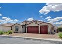 Tan three-car garage home with red doors and brick driveway at 8357 Sonora Del Sol St, Las Vegas, NV 89113