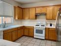 Kitchen with wood cabinets, white appliances, and tile flooring at 6140 Natural Slope St, Las Vegas, NV 89148