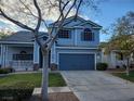 Two-story house with blue siding, attached garage, and landscaping at 7621 Natures Song St, Las Vegas, NV 89131