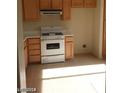 Bright kitchen featuring light wood cabinets, white appliances, and tile flooring at 10404 Frostburg Ln, Las Vegas, NV 89134