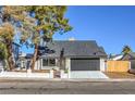 House exterior with a dark garage door and landscaping at 7152 Parasol Ln, Las Vegas, NV 89147