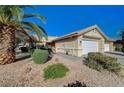 Front view of a single-story house with a two-car garage and palm trees at 2035 E Warm Springs Rd # 1019, Las Vegas, NV 89119