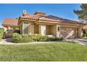 Spanish style home with tile roof, landscaping, and two car garage at 8050 Castle Pines Ave, Las Vegas, NV 89113