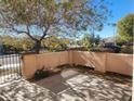 Neat front patio with a gate, small wall, and a tree providing shade at 2652 Rue Marquette Ave, Henderson, NV 89044