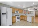 Cozy kitchen featuring wood cabinets, white appliances, and tile flooring at 501 Riata Way, Las Vegas, NV 89110