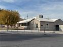 Tan house with a white roof and chain link fence, a tree with yellow leaves in front at 820 Judson Ave, North Las Vegas, NV 89030