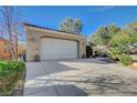 Tan house with a white garage door and nicely landscaped front yard at 5721 Keystone Crest St, North Las Vegas, NV 89081