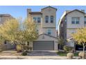 Three-story house with gray siding, a two-car garage, and landscaping at 805 N Water St, Henderson, NV 89015