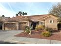 Single-story home with a tile roof, three-car garage, and desert landscaping at 427 Norridgewock St, Henderson, NV 89074