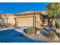 Single-story home with a tan exterior, landscaped yard, and two-car garage at 7616 Fruit Dove St, North Las Vegas, NV 89084