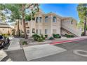 Front view of a two-story condo building with a paved driveway, landscaping, and trees at 7400 W Flamingo Rd # 1006, Las Vegas, NV 89147