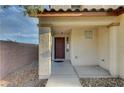 Covered front entry with a brown door, concrete walkway, and gravel landscaping at 10353 Cherokee Corner Ave, Las Vegas, NV 89129