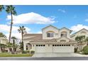 Two-story house with beige exterior, two-car garage, and palm trees at 2941 Harbor Cove Dr, Las Vegas, NV 89128