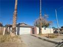 Another view of the home's front exterior with attached garage, driveway, and palm trees at 2500 Holly Ave, Las Vegas, NV 89106