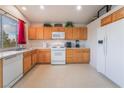 Kitchen features wood cabinets, white appliances, and tile flooring at 1808 Quartz Landing Ave, Las Vegas, NV 89183