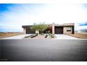 Front view of a modern home with a desert landscape and a two-car garage at 6059 E Spring Mountain Blvd, Pahrump, NV 89048