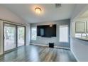 Living room with large TV, sliding glass doors, wood-look floors, and view of the backyard at 488 Eagle Vista Dr, Henderson, NV 89012