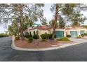 Tan house with tile roof, green garage door, and mature trees at 2714 Bridgepointe Dr, Las Vegas, NV 89121