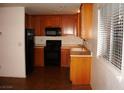 Galley kitchen with wood cabinets, black appliances, and tile floor at 3367 Villa Fiori Ave, Las Vegas, NV 89141