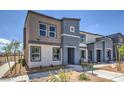 Two-story townhome, featuring gray and tan siding, landscaping, and a bench at 5021 Apple Mesa Ave # Lot 222, Las Vegas, NV 89139