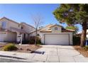 Two-car garage and driveway, well-maintained front yard, and desert landscaping at 5467 Morning Swim Ln, Las Vegas, NV 89113