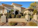 House entrance with an arched doorway, stonework, and lush landscaping at 2111 Bogart Ct, Las Vegas, NV 89117