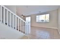 Living room with tiled floors, white staircase, and sliding glass door access at 9512 Canyonland Ct, Las Vegas, NV 89147