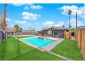 Inviting backyard oasis featuring a refreshing blue swimming pool and lush green lawn at 709 Osprey Cir, Las Vegas, NV 89107