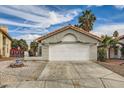 Single story house with a white two-car garage and gravel driveway at 2668 Alwoodley Cir, Las Vegas, NV 89142