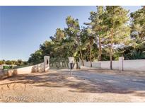 Gated entrance to a property with mature trees and a white block wall at 7080 S Pecos Rd, Las Vegas, NV 89120