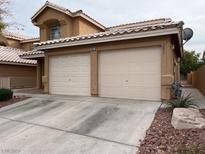 Two-car garage and front entry of tan two-story house at 8009 Draco Cir # 201, Las Vegas, NV 89128