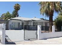Charming single-story home featuring a gated yard, covered porch, and beautiful palm trees at 215 N Bruce St, Las Vegas, NV 89101