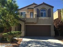 Two-story house with a brown garage door and balcony at 10225 Headrick Dr, Las Vegas, NV 89166