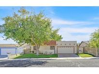 Single-story home with a large tree, attached garage, and gated entry at 5135 Brownwood Ave, Las Vegas, NV 89122