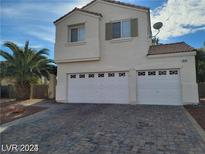 Two-story house with a three-car garage and brick paver driveway at 7879 Villa Pintura Ave, Las Vegas, NV 89131