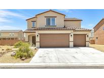 Two-story home with tan exterior, two car garage and landscaping at 3929 E Weld Ave, Pahrump, NV 89061