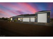 Luxury custom home with a three-car garage at dusk at 1440 E Gamebird Rd, Pahrump, NV 89048