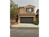 Two-story house with a dark gray garage door and tan exterior at 10425 Scotch Elm Ave, Las Vegas, NV 89166